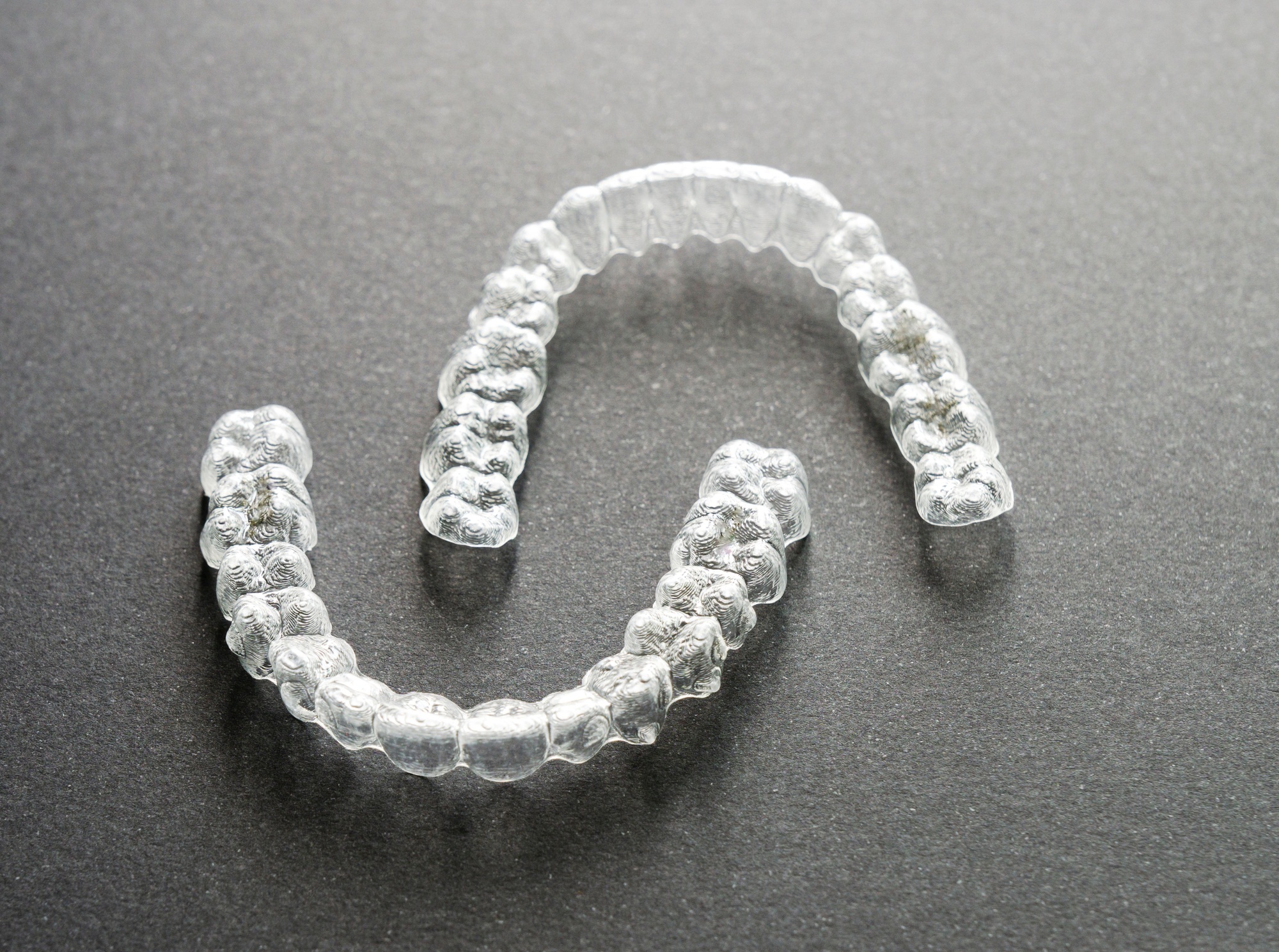 Close-up of clear orthodontic aligners splints on a gray surface