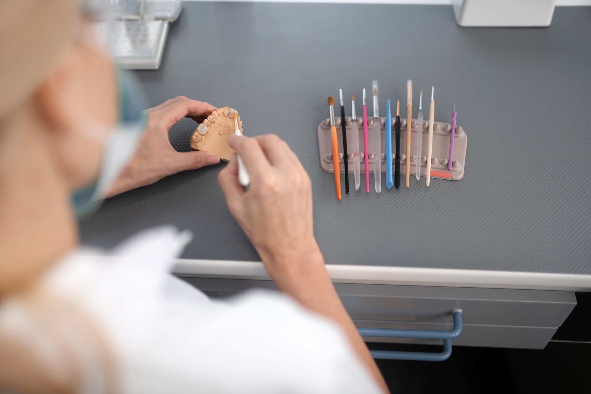 Dental technician using brushes to clean porcelain prosthesis