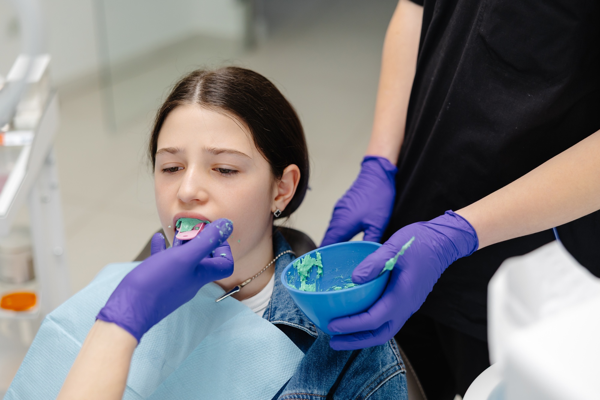 Dentist applying dental sealant on teeth of teenage girl
