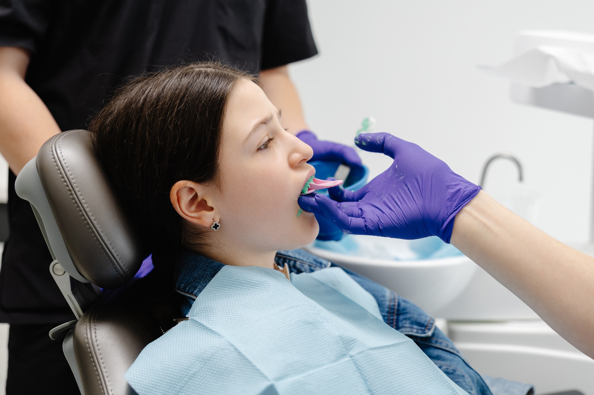 Dentist applying dental sealant on teeth of teenage girl