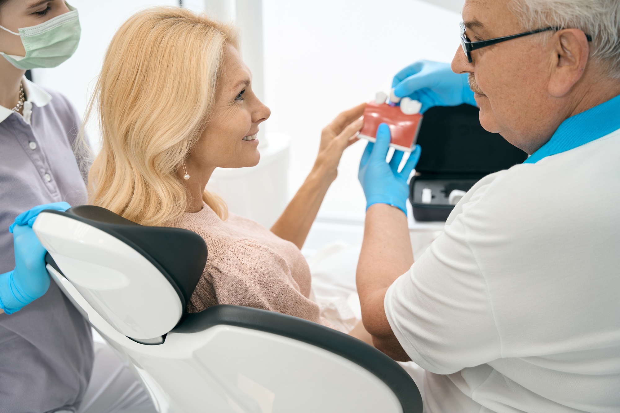 Dentist holding model of teeth with dental implant