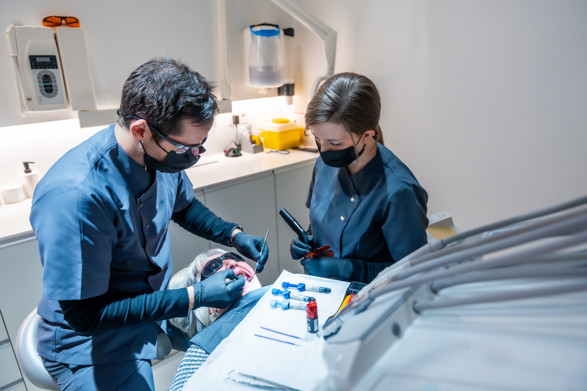 Dentist performing teeth whitening procedure on patient in modern clinic