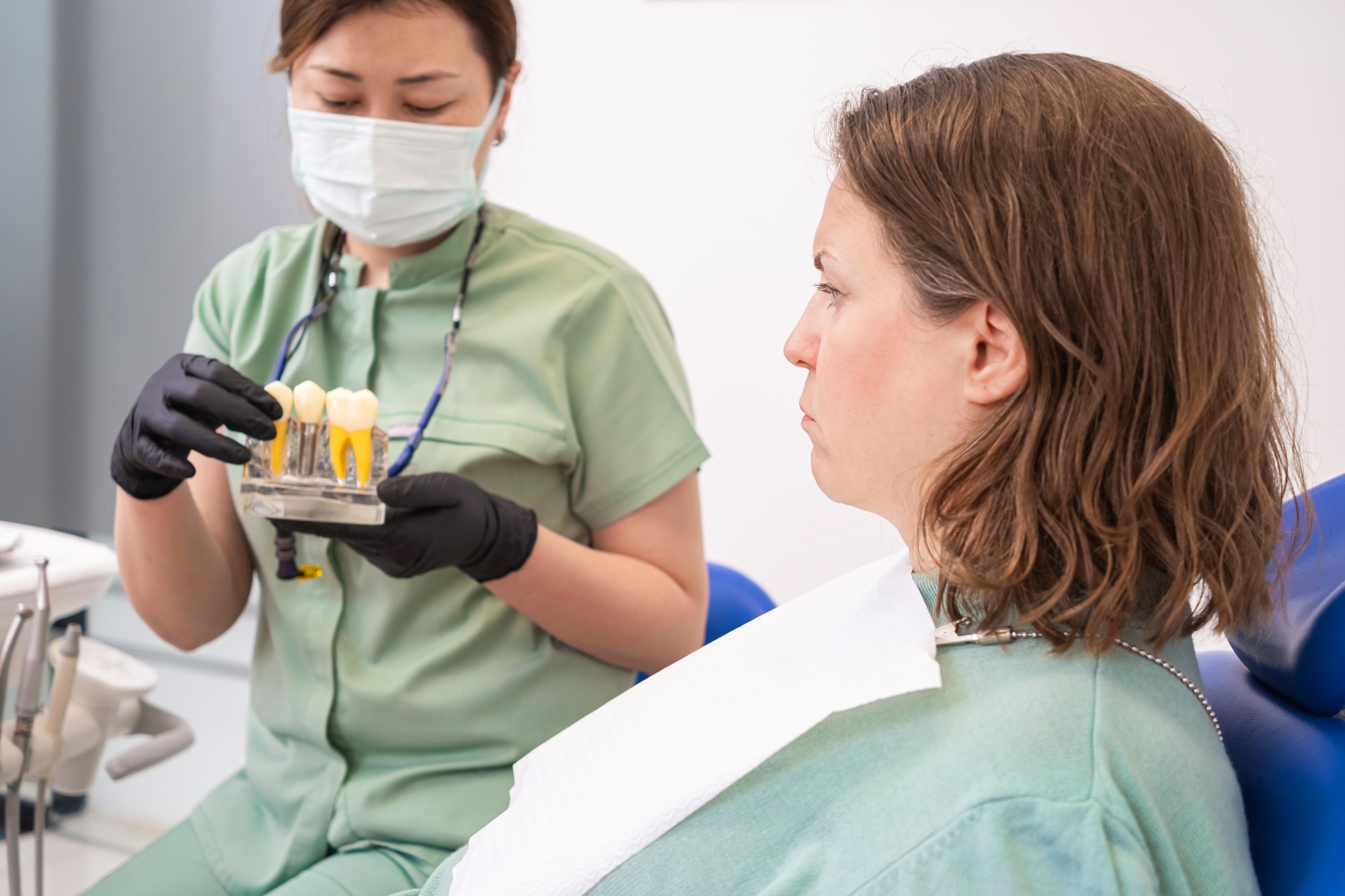 Stomatologist with patient discussing benefits of dental implant surgery, types of dental implants