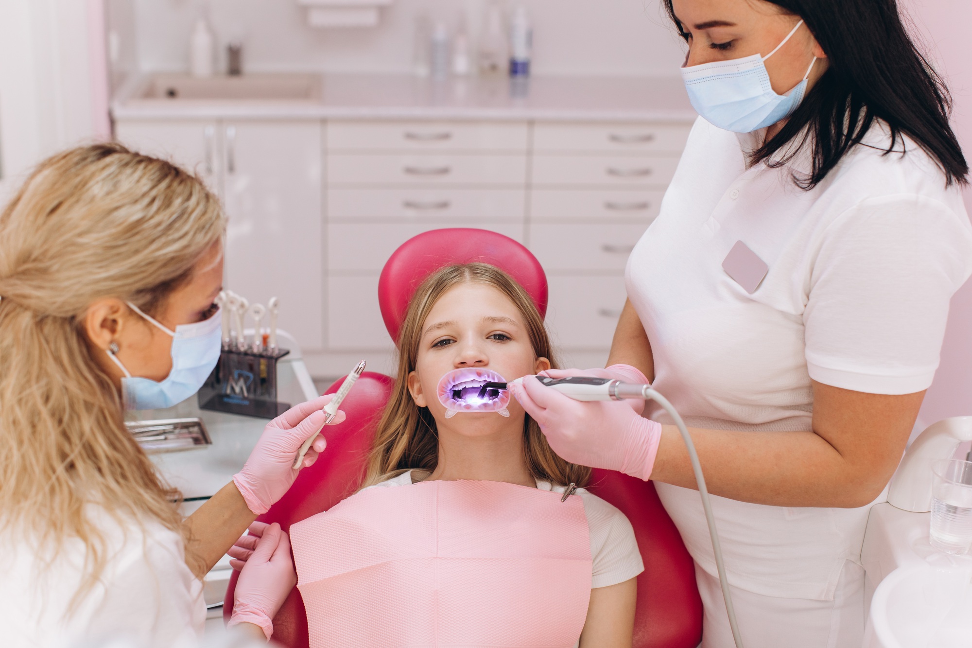Teenage girl doing ultraviolet teeth whitening at a dental clinic