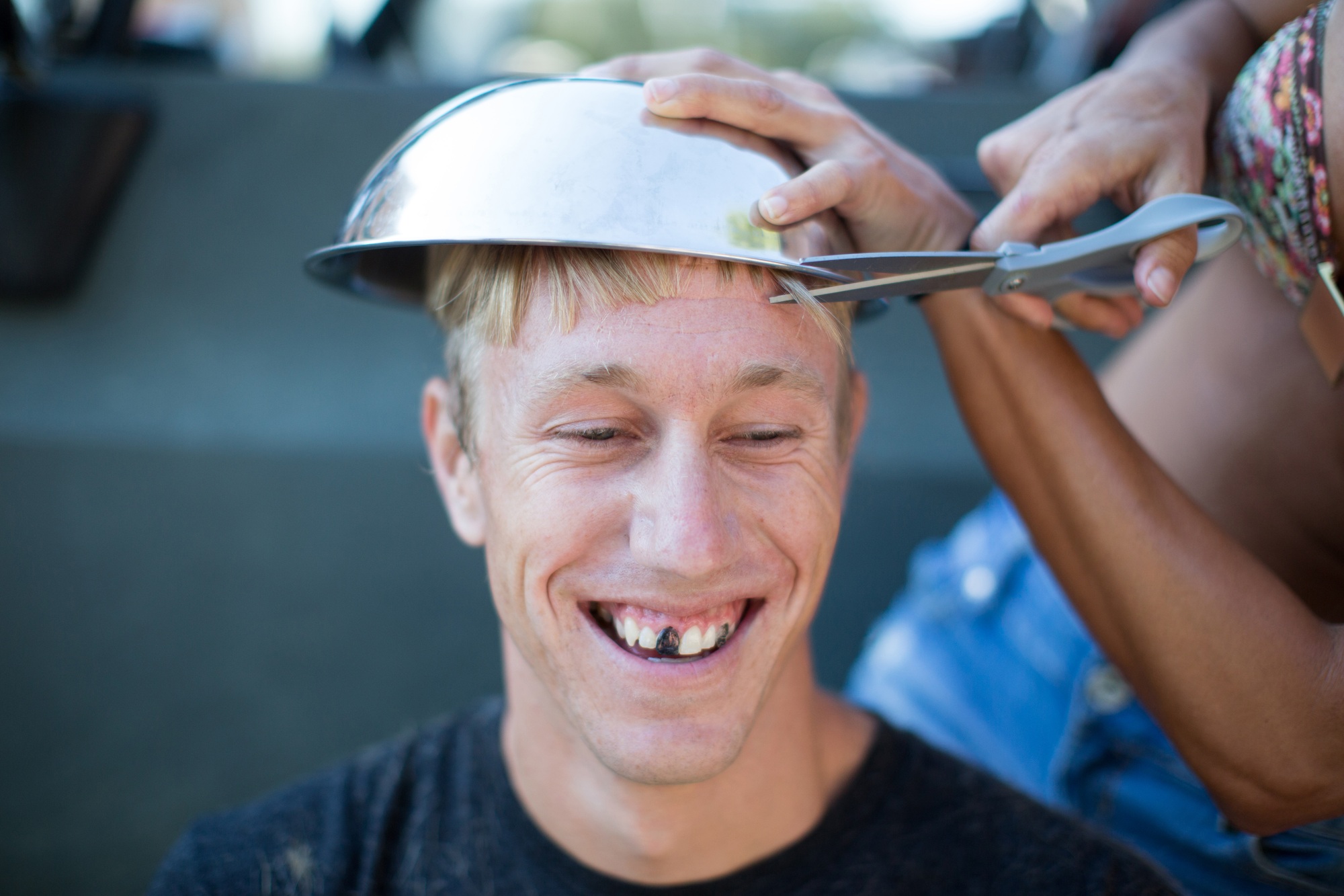 Woman cutting young man's hair using bowl, man's teeth blacked out