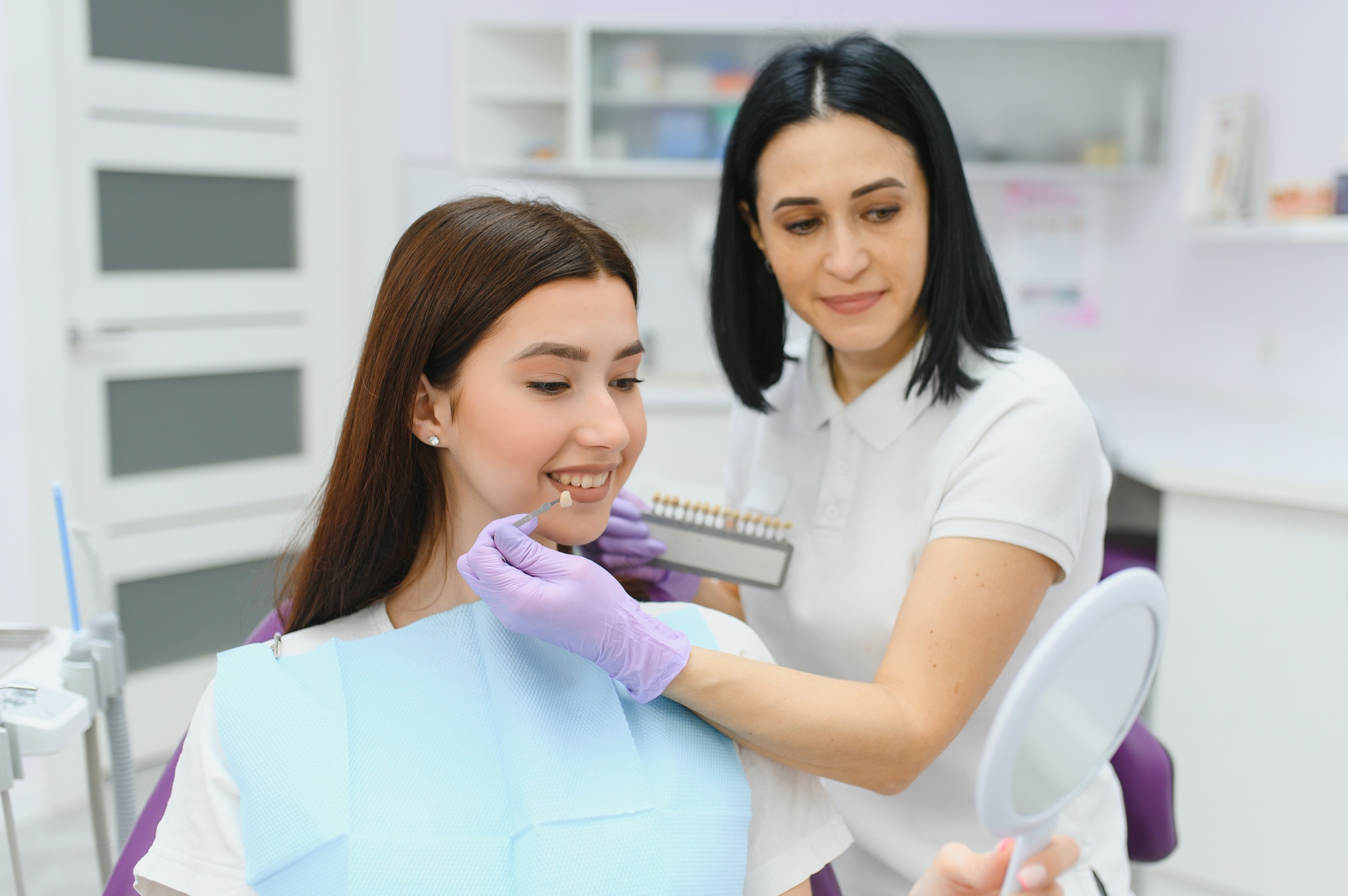 Young woman choosing color of teeth at dentist