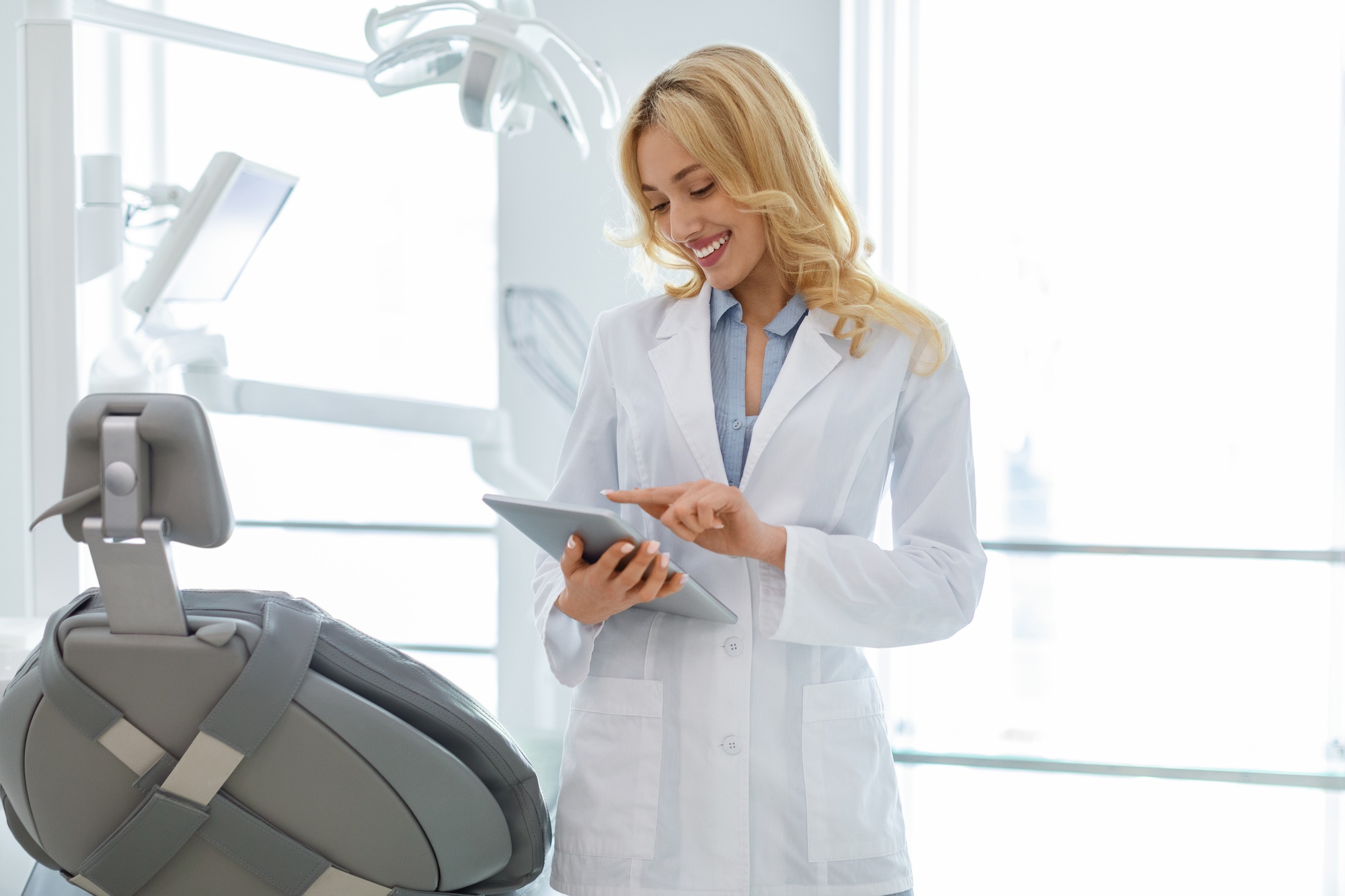 Blonde woman dentist using digital tablet at dental clinic
