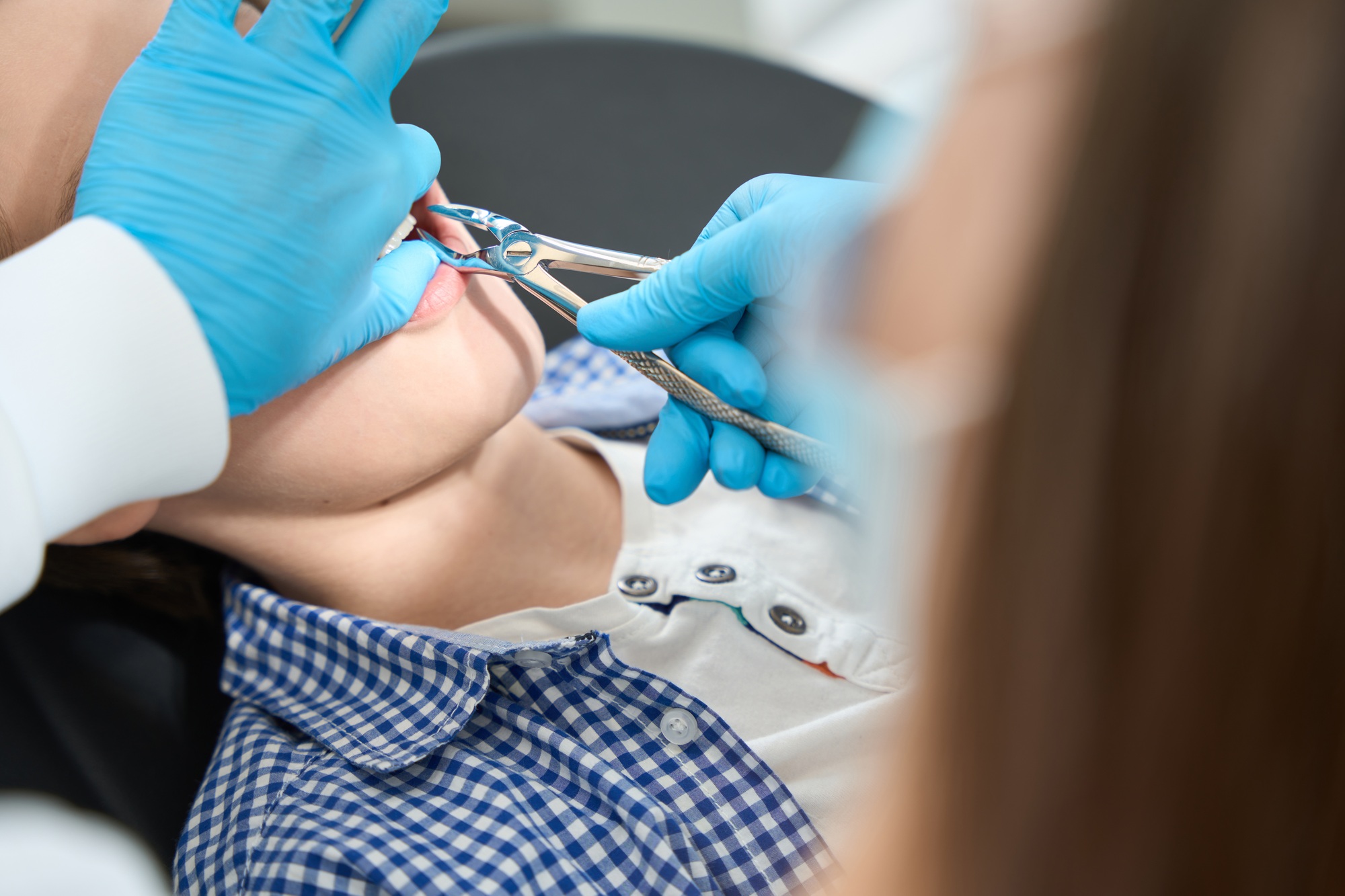 Child is removed tooth in medical institution with special tool
