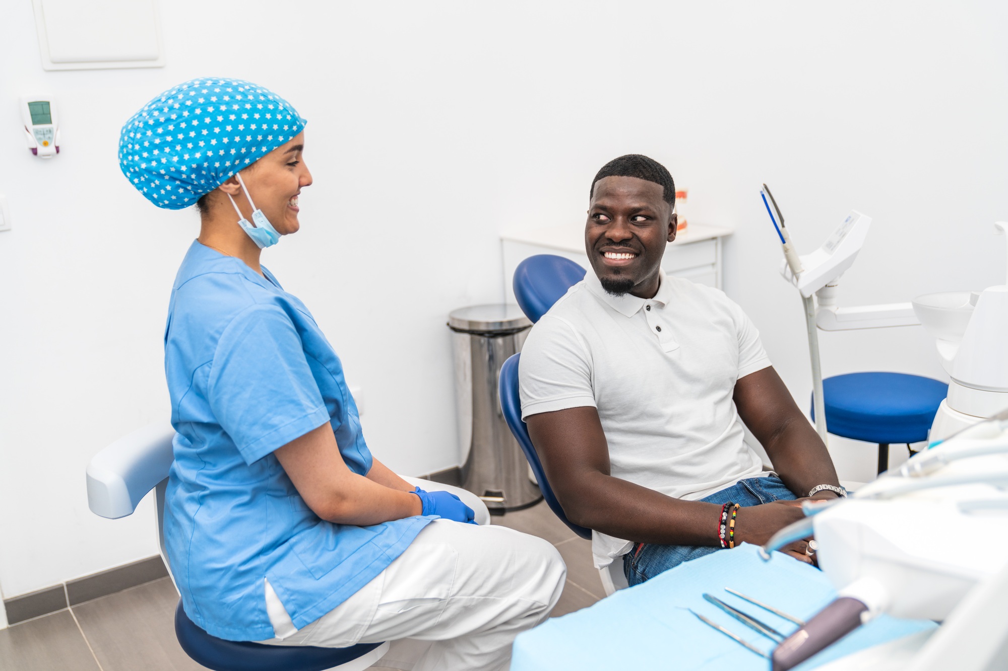 Dental hygienist and African male patient having a pleasant conversation before dental treatment.