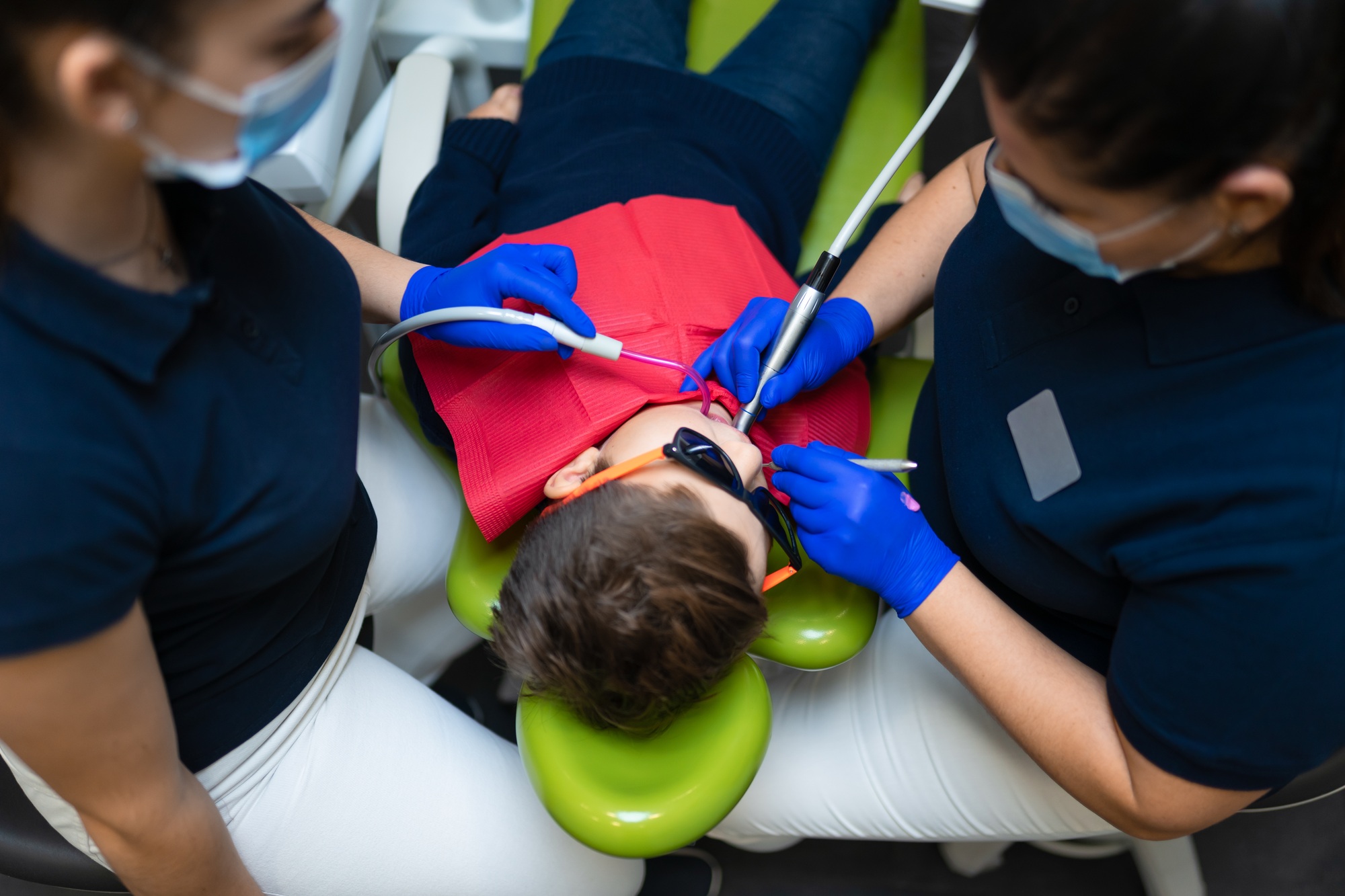 Dentist and assistant make preventive dental plaque cleaning for teenager