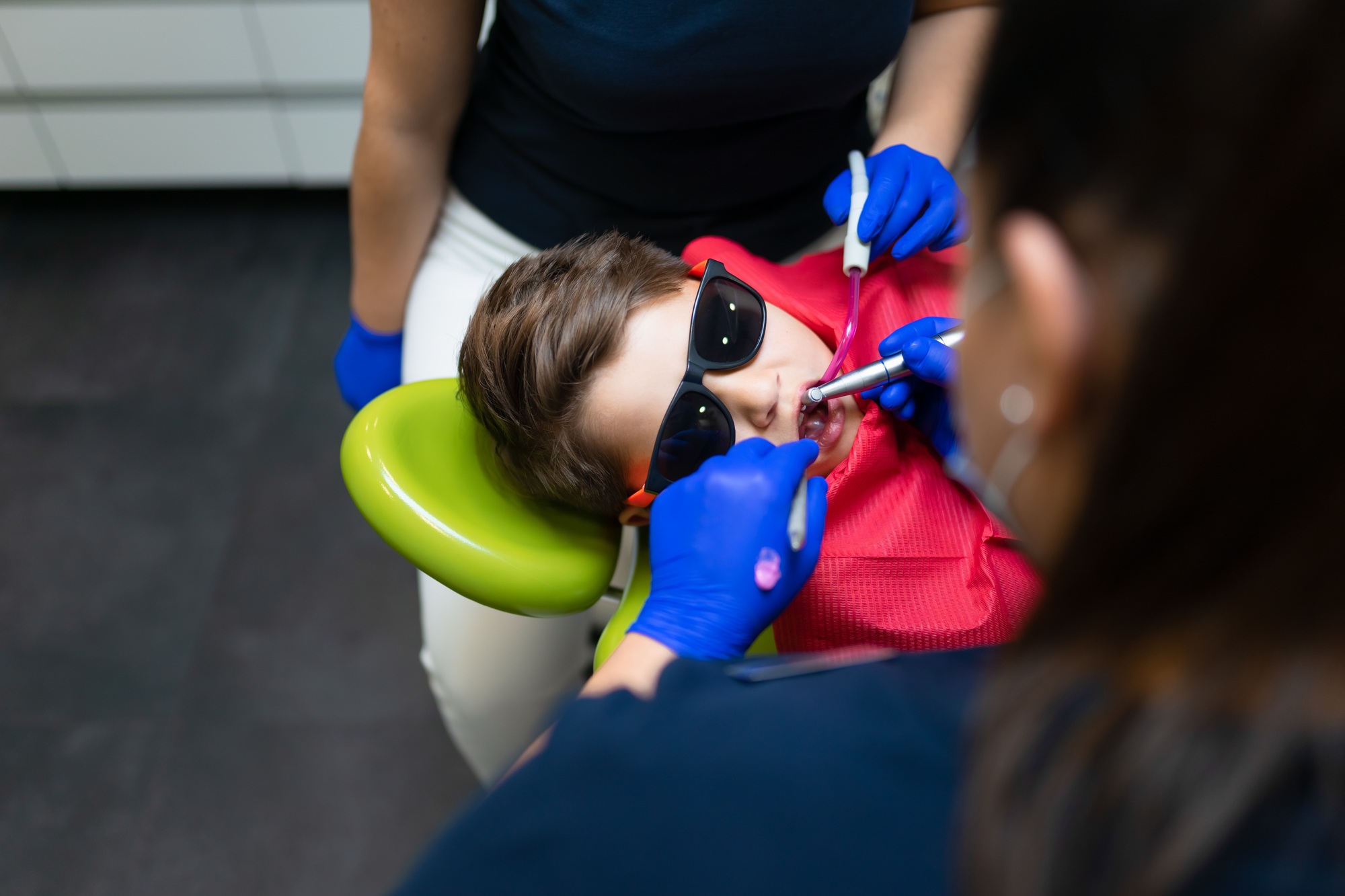 Dentist and assistant make preventive dental plaque cleaning for teenager