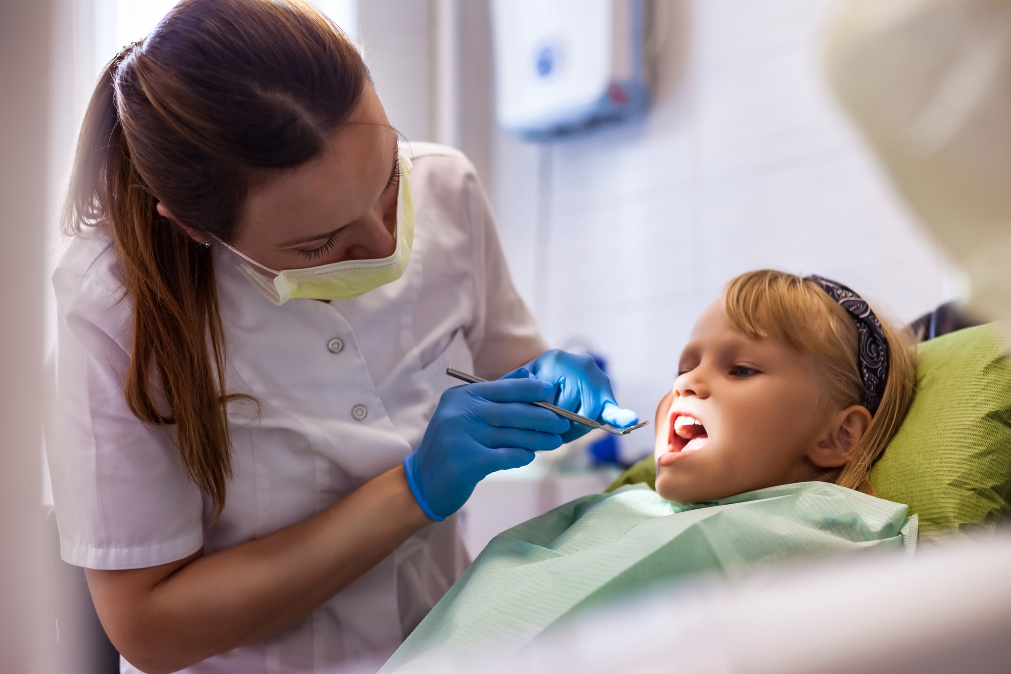Dentist doing teeth checkup at dental office for adorable girl in children dentistry