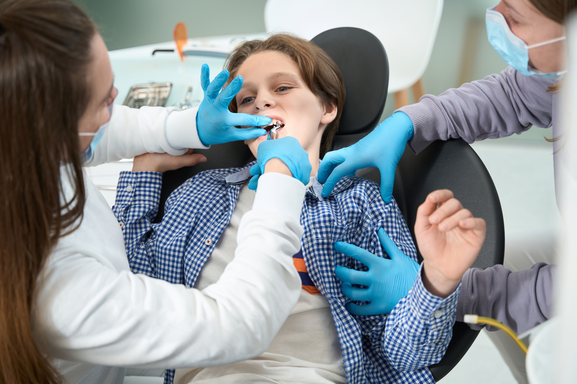Dentist-surgeon removes a tooth to a teenager with special tool