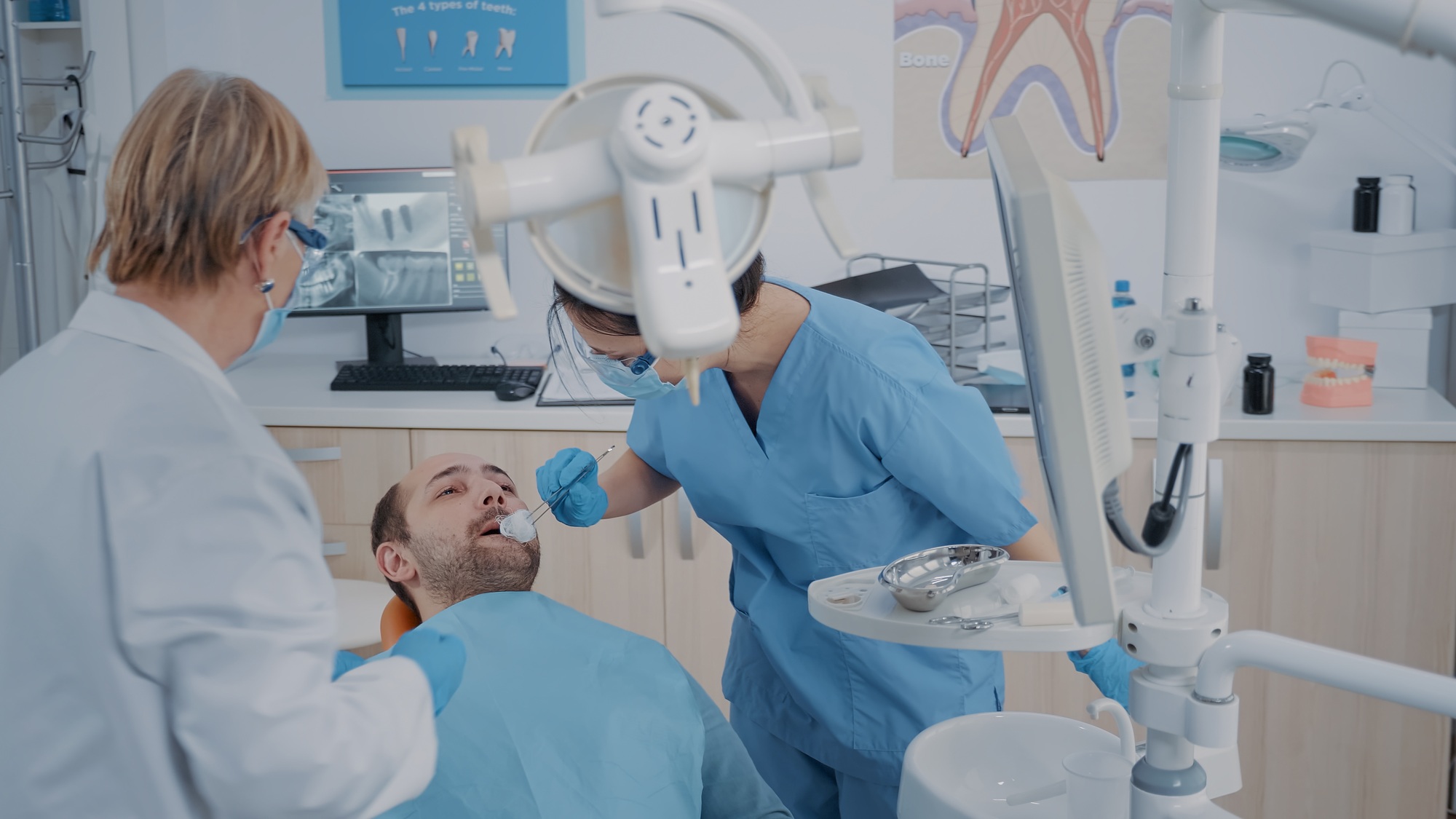 Dentistry team performing tooth extraction in stomatology cabinet