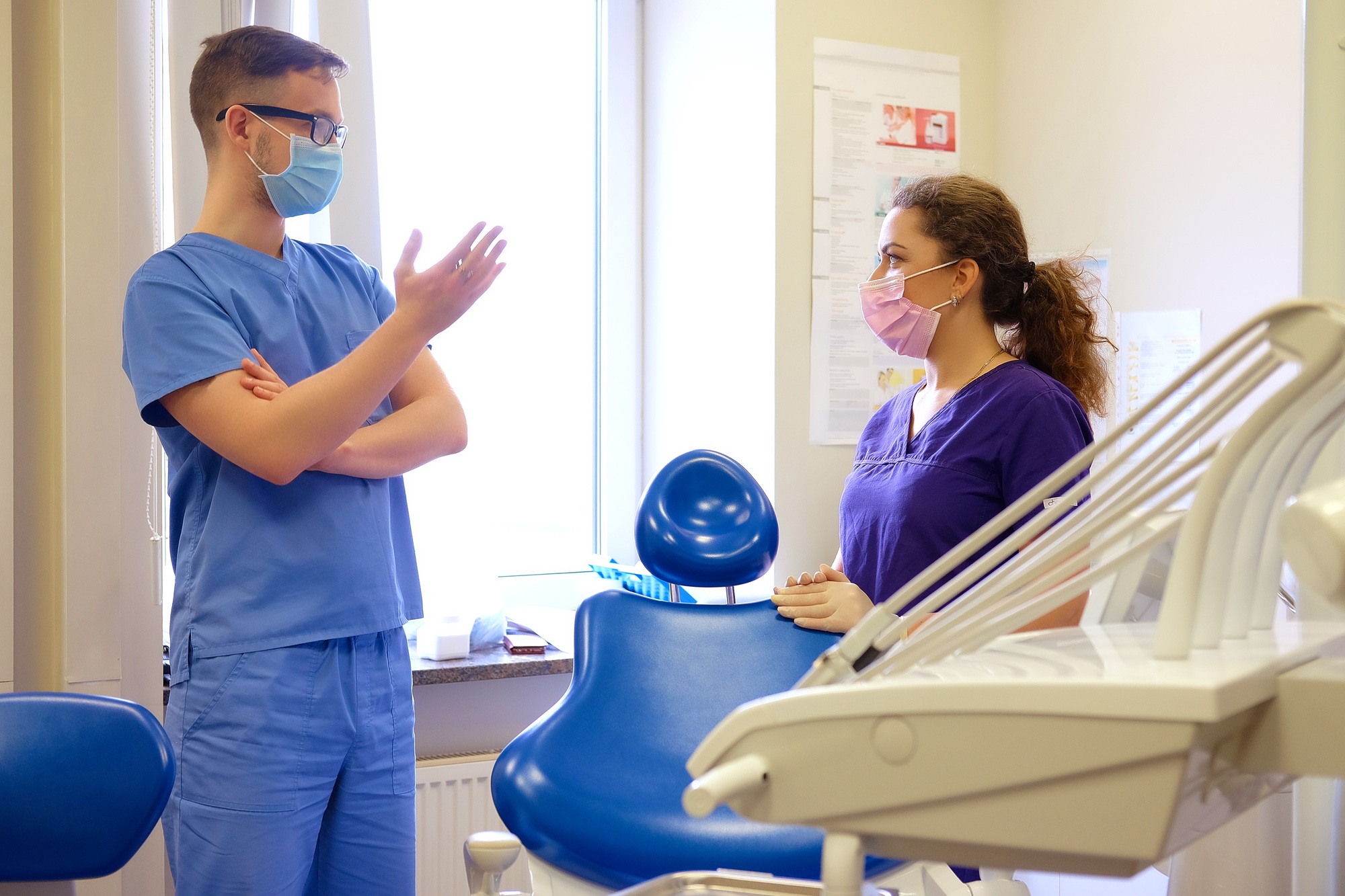 Handsome male dentist speaks with a female assistant at a clinic.