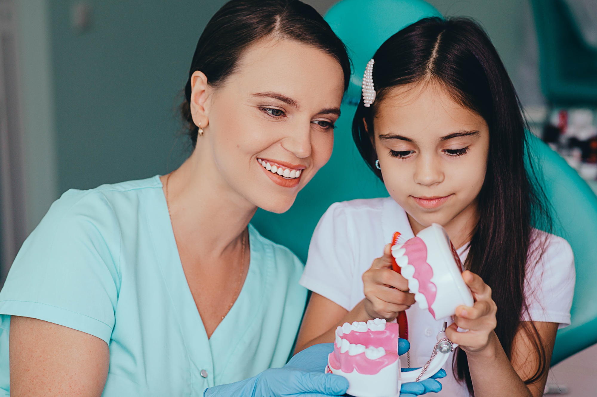 Little girl and pediatric dentist at dental clinic. Dentist having fun with little patient