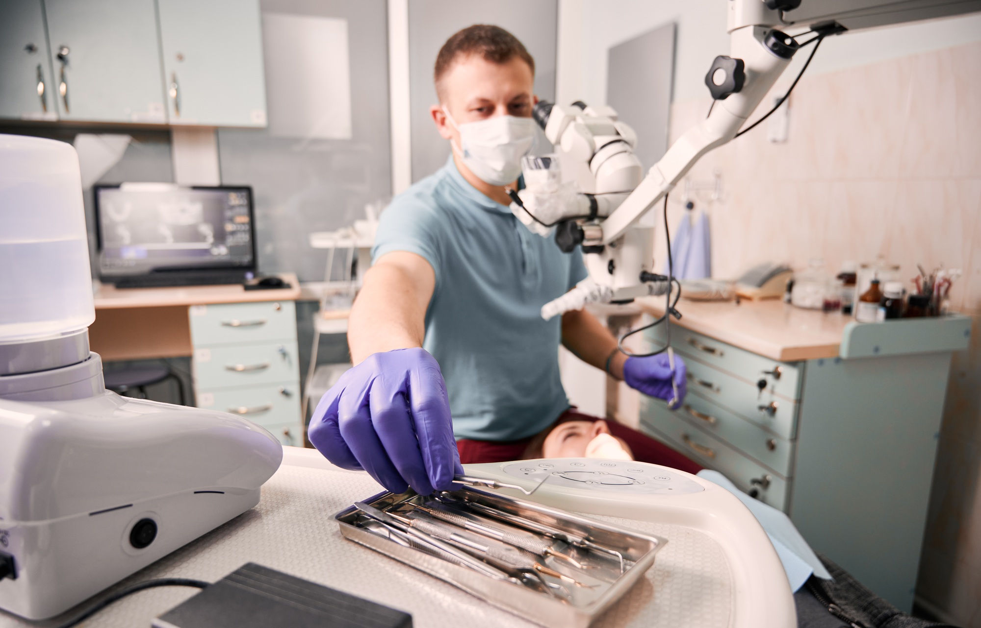 Male dentist grabbing dental explorer during dental procedure.