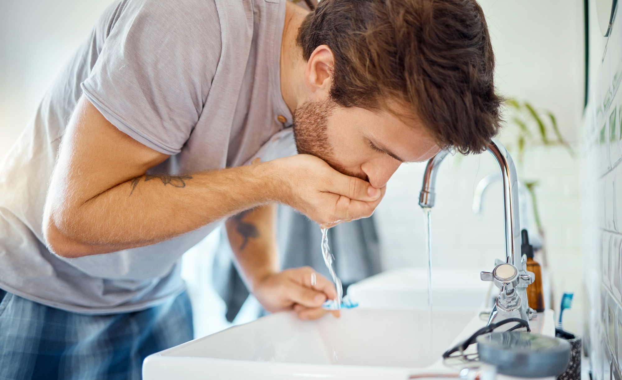 One handsome man rinsing his mouth in a bathroom at home. Caucasian male using mouthwash for fresh
