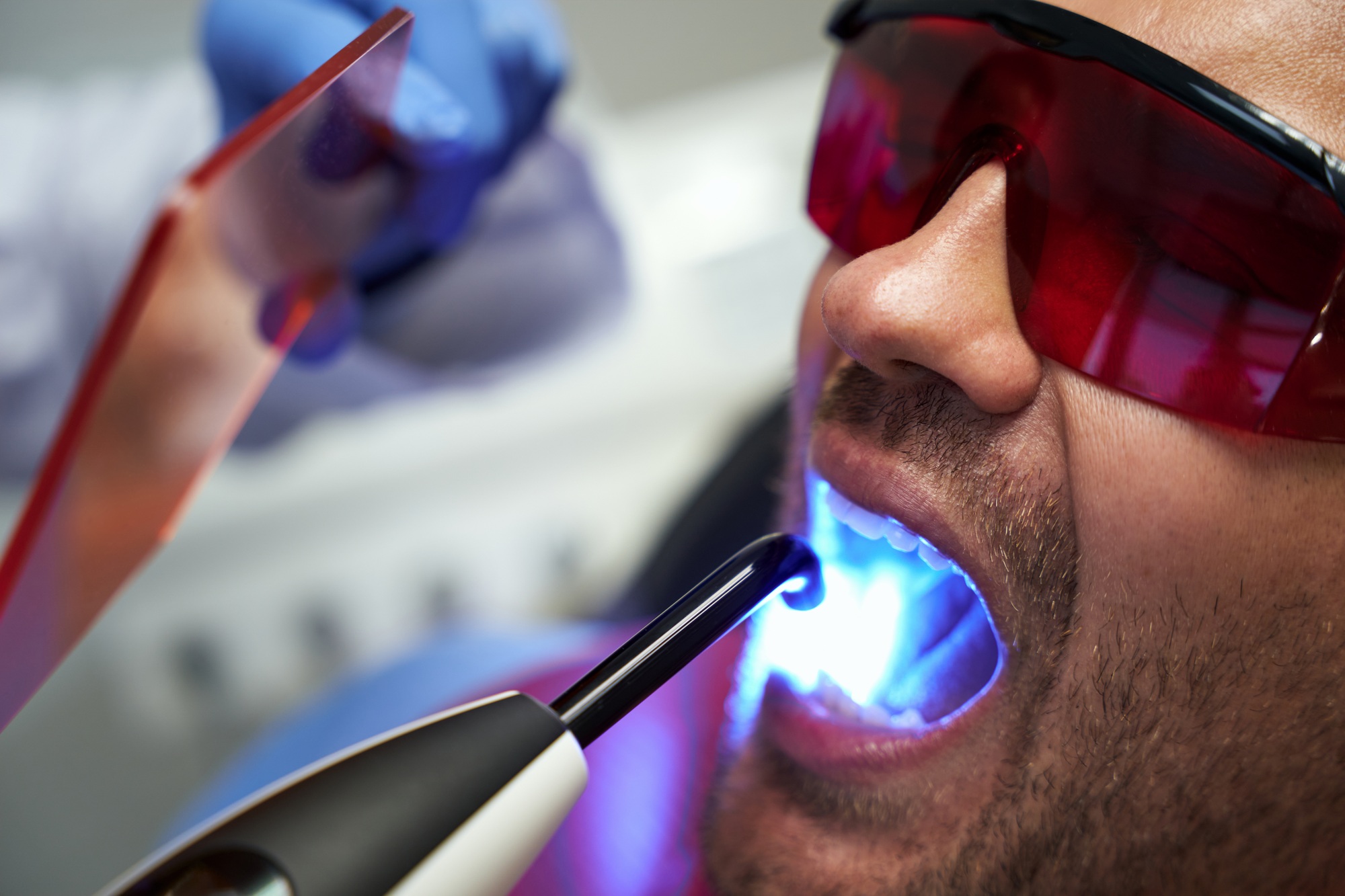 Patient in glasses receiving laser dental treatment at clinic