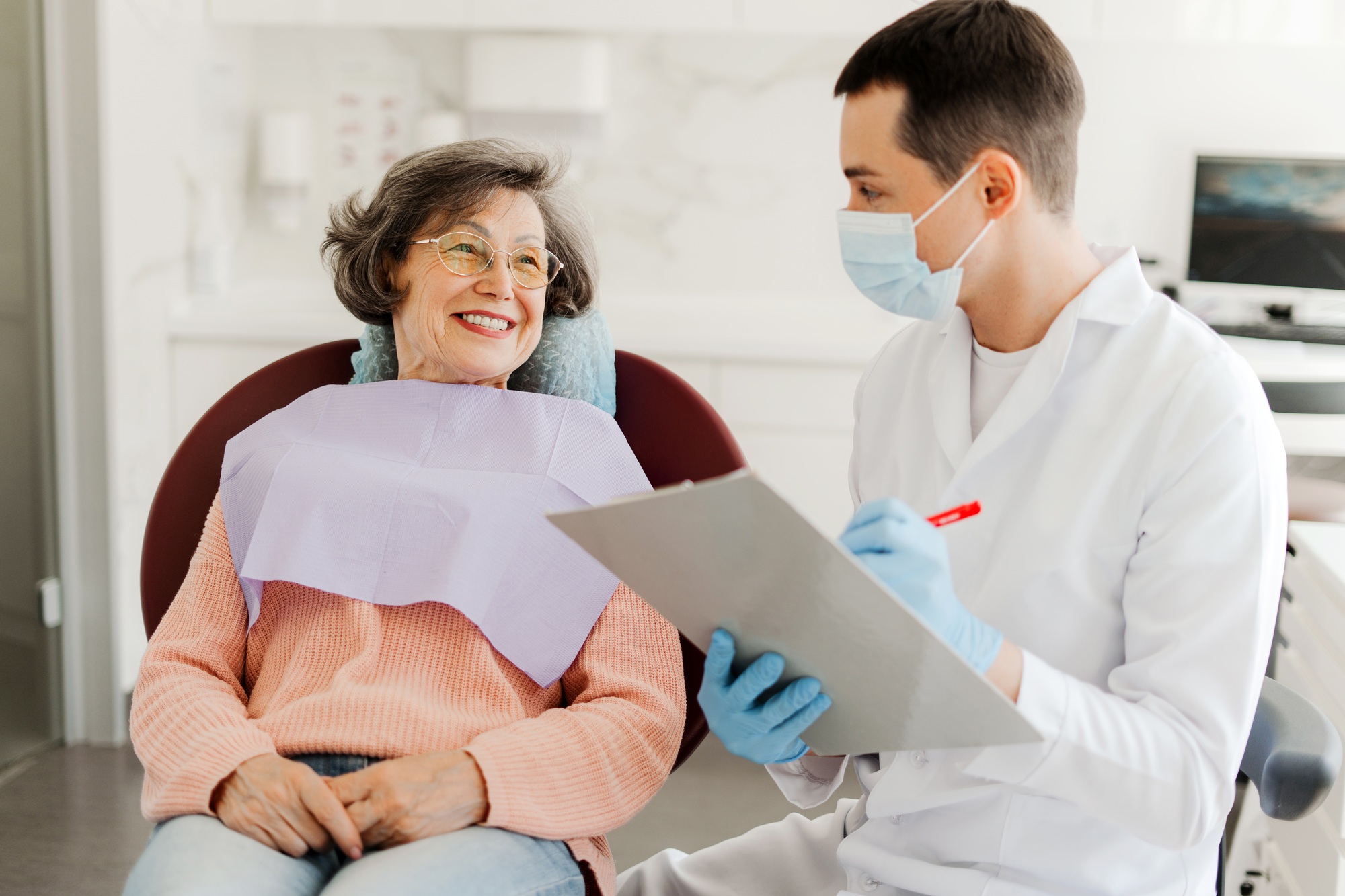 Senior woman, patient visiting professional doctor, talking, dentist writing down complaints