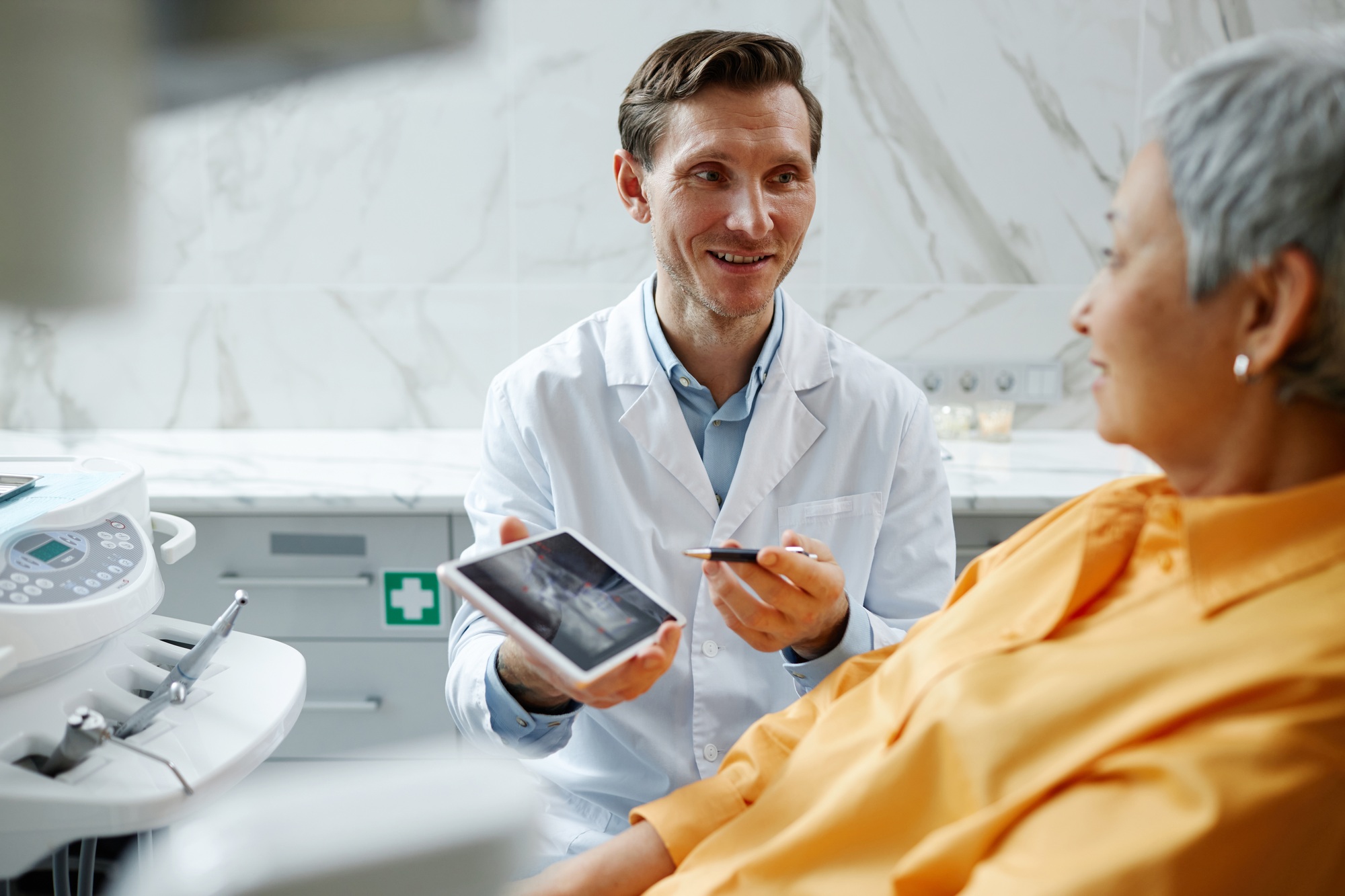 Smiling male dentist holding digital tablet with teeth x-ray image