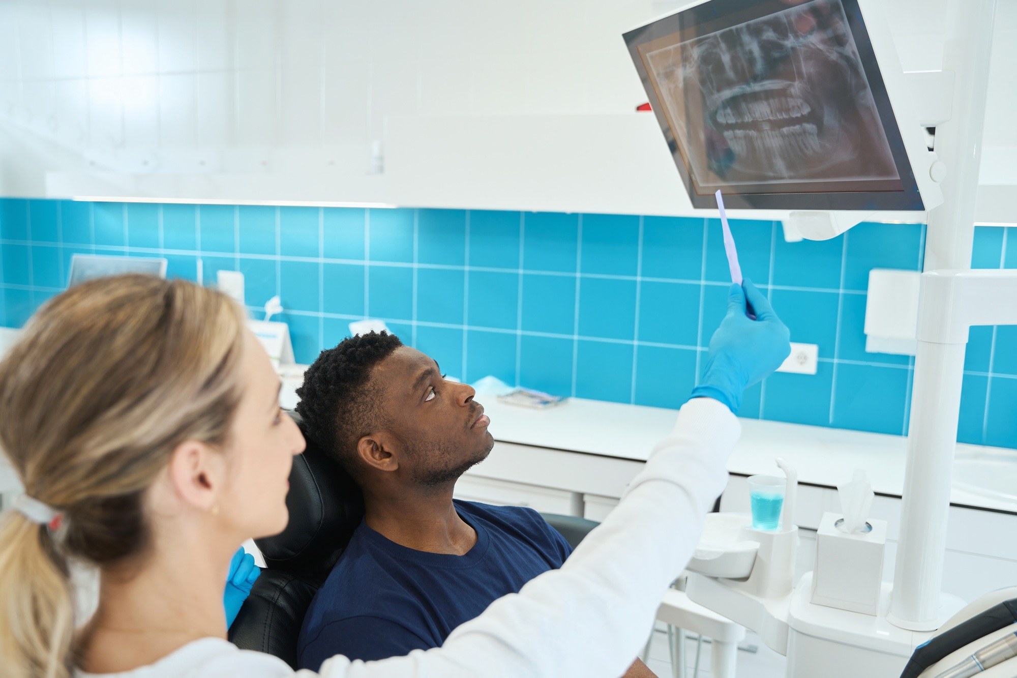 Stomatologist showing to client digital screen with x-ray image of his jaw