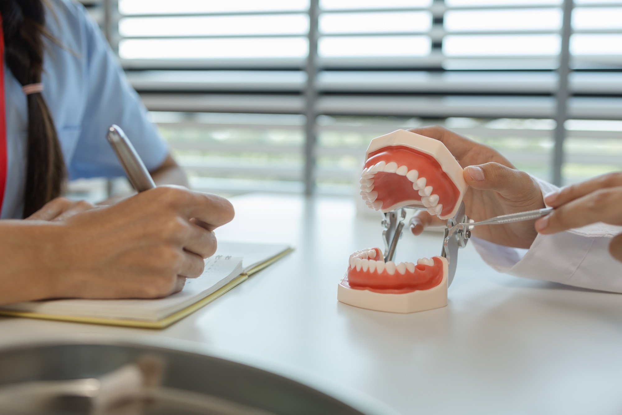 the dentist is explaining to the assistant how she will treat a patient with wisdom teeth