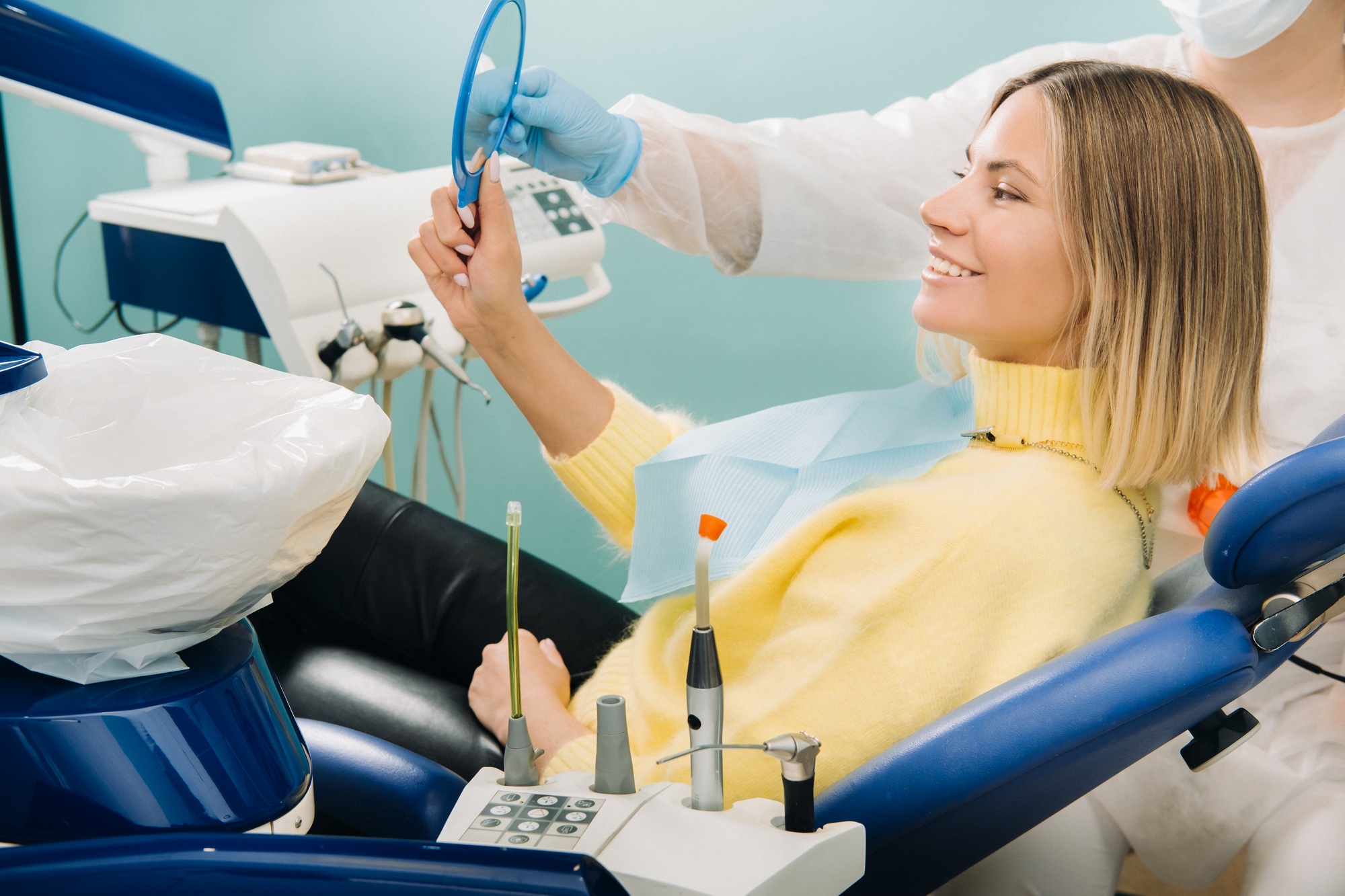 The girl smiles and looks in the mirror in dentistry