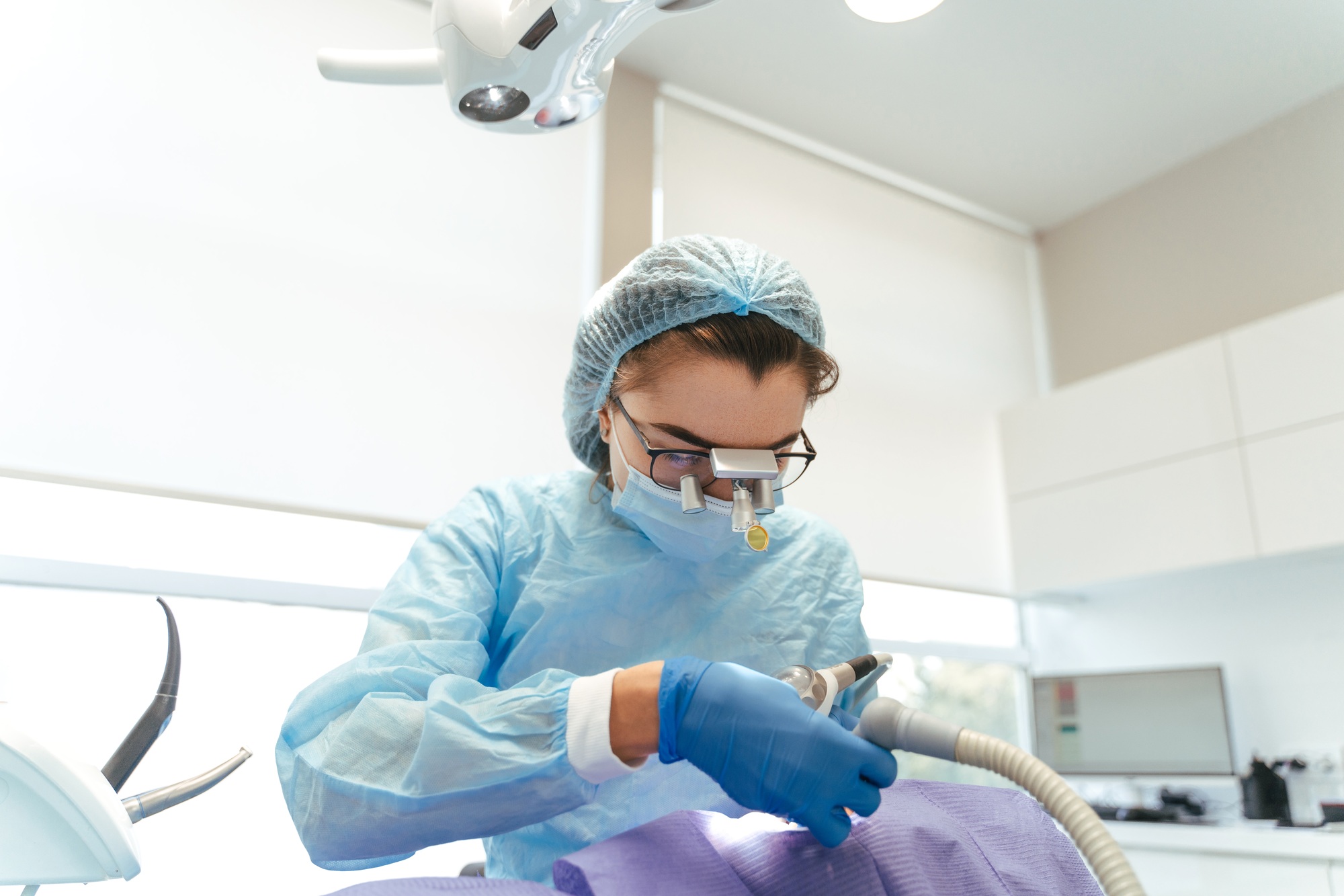 Woman dentist in protective clothes making professional teeth cleaning