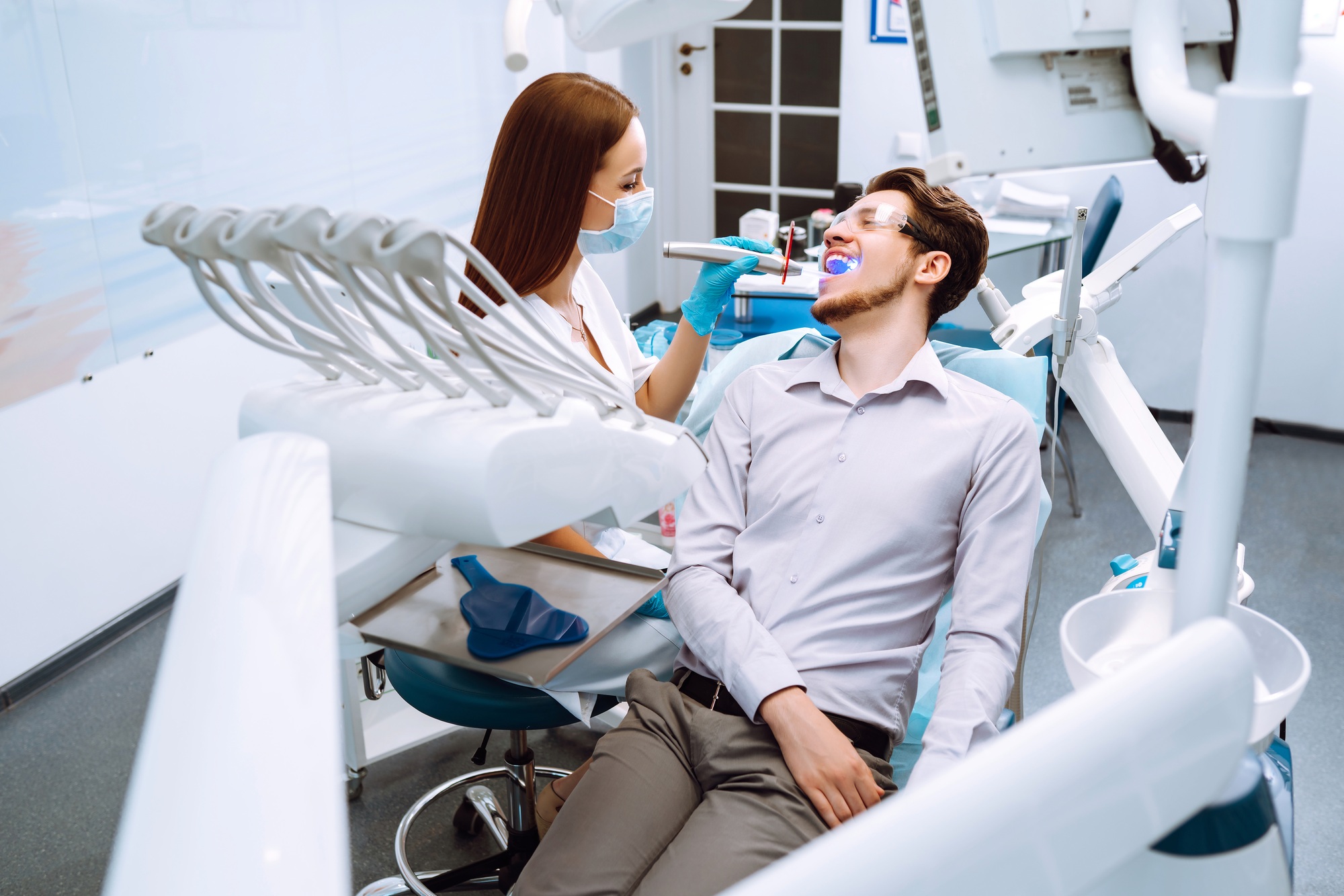 Young man at the dentist's chair during a dental procedure. Overview of dental caries prevention.
