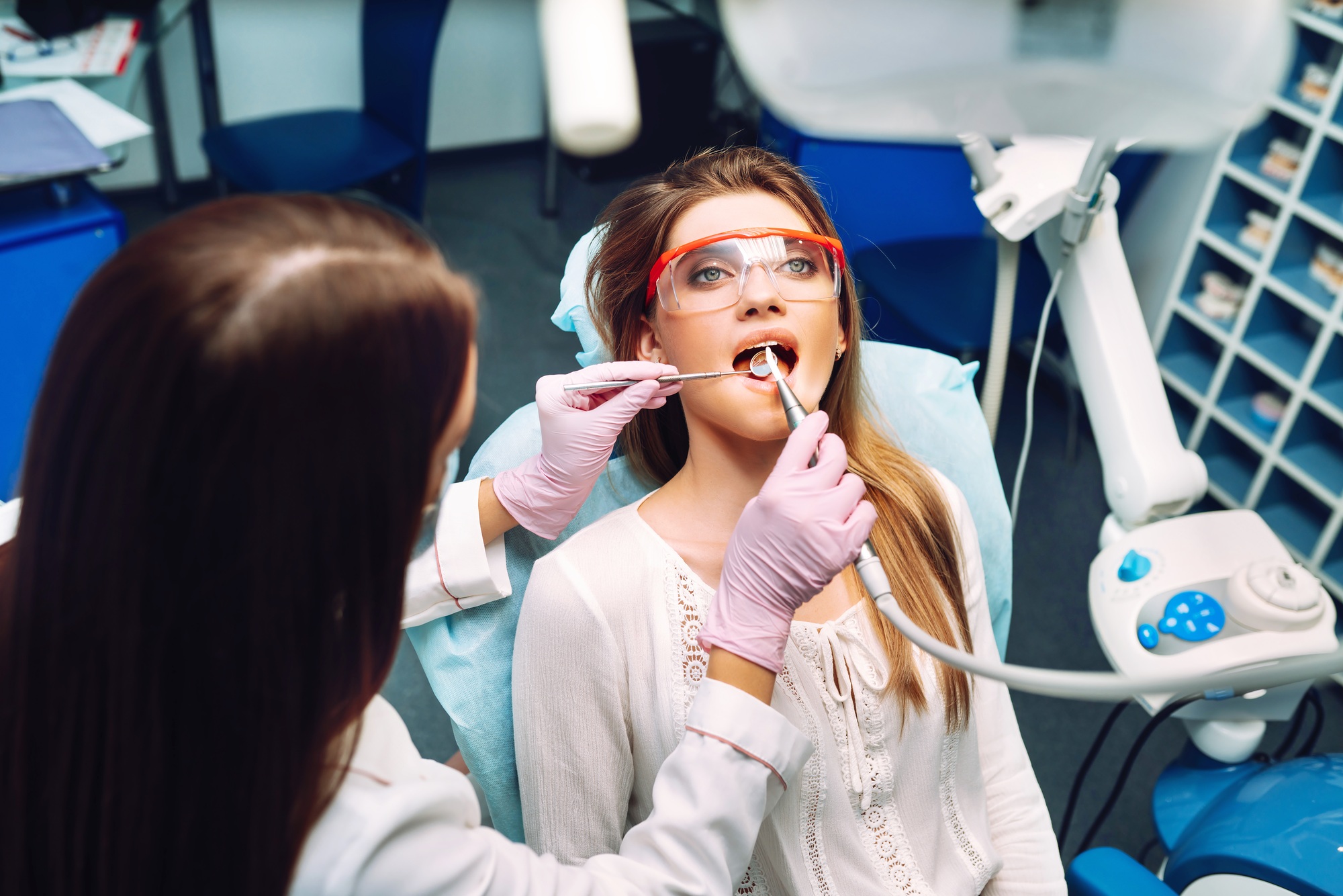 Young woman at the dentist's chair during a dental procedure. Overview of dental caries prevention.
