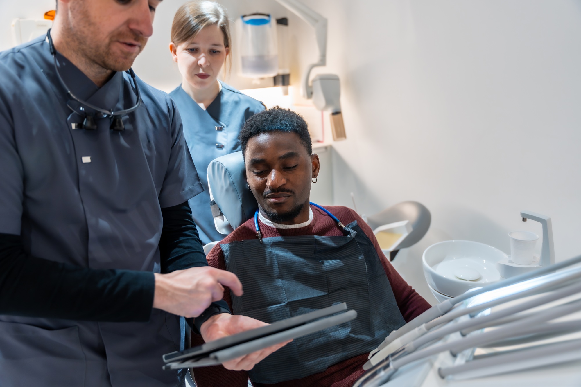Dentist showing results on tablet to patient in dental clinic Dentist showing results on tablet to patient in dental clinic