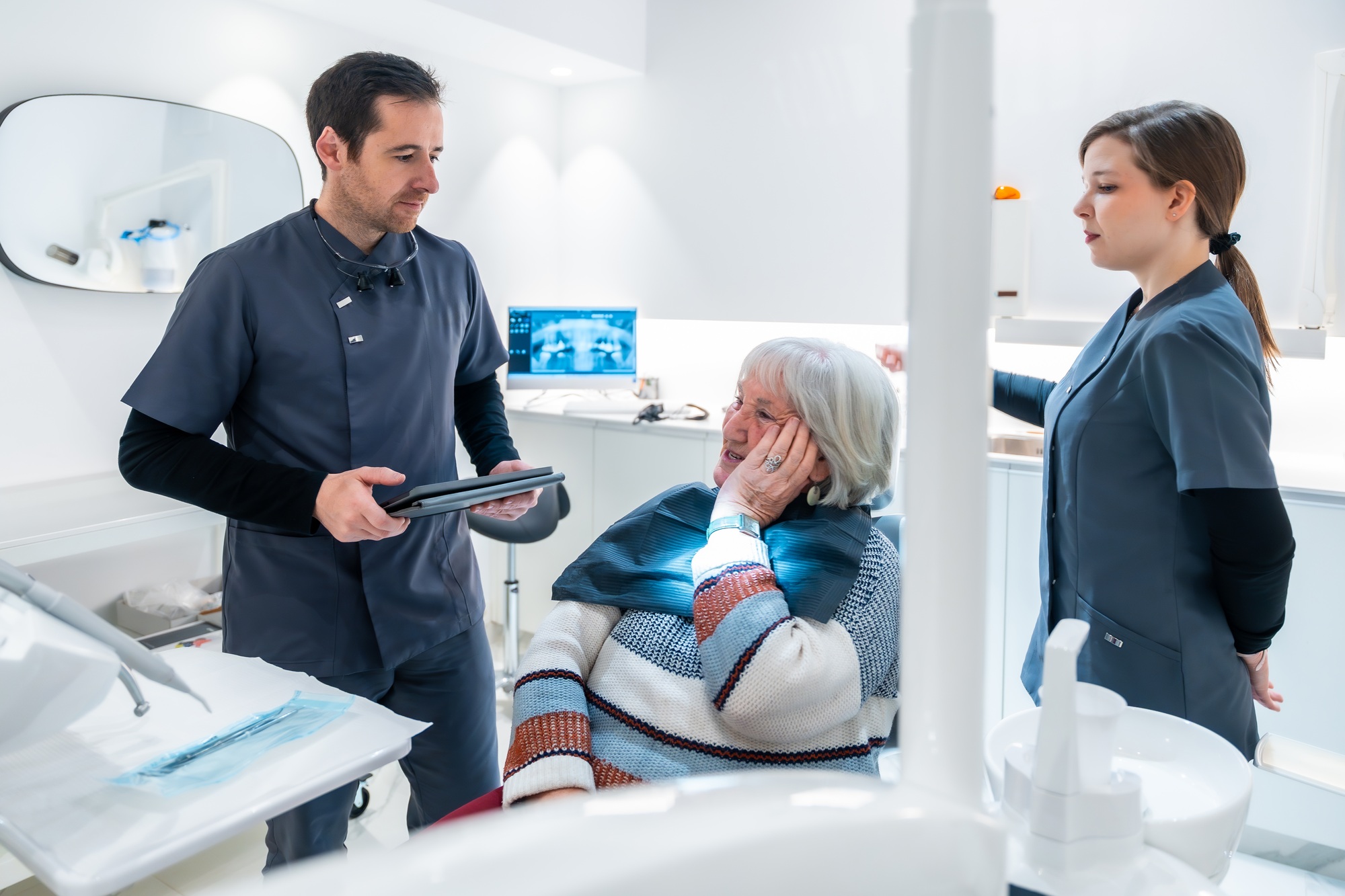 Dentist showing results on tablet to senior woman in dental clinic
