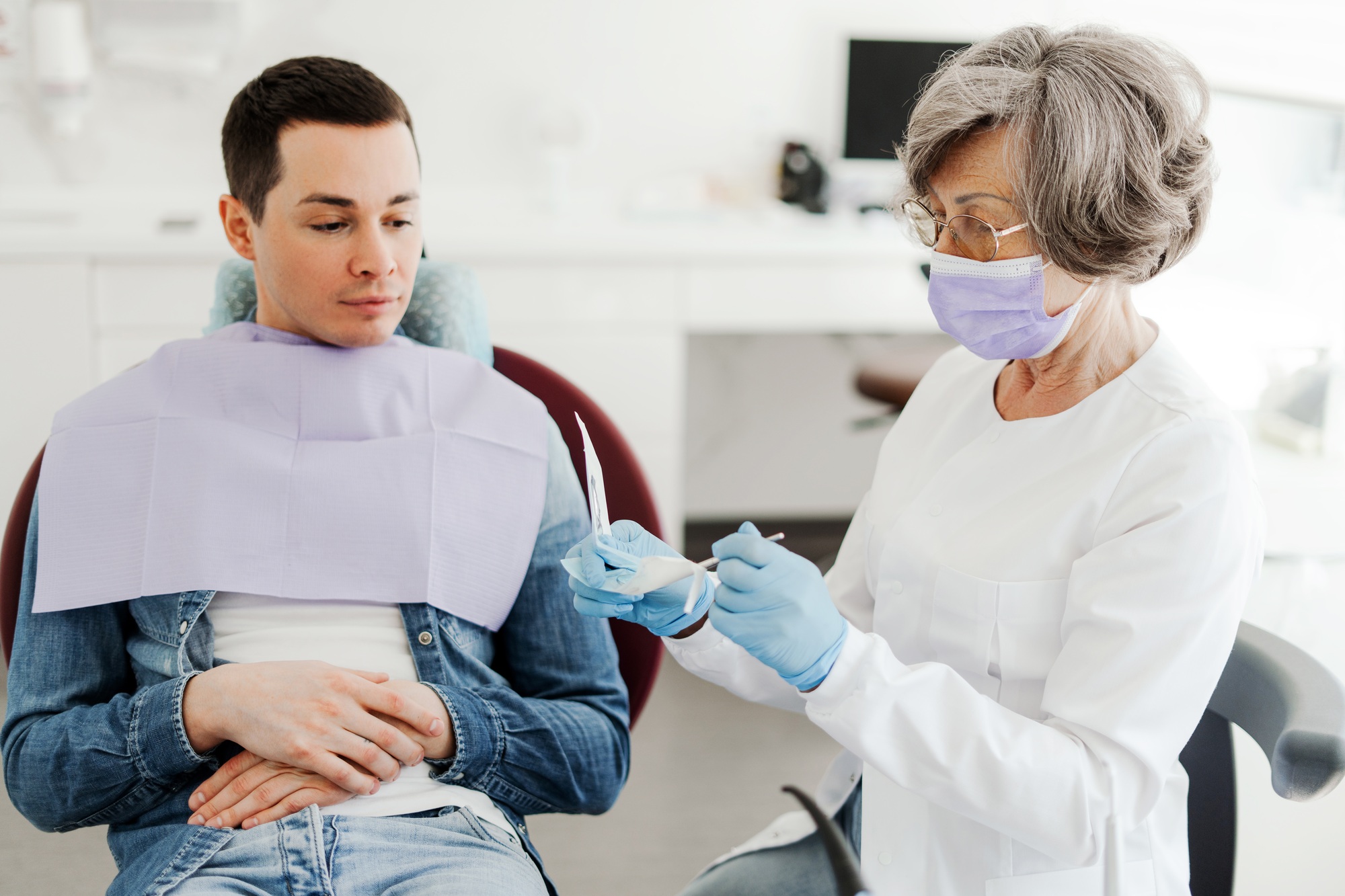 Experienced, senior dentist, attractive woman holding dental equipment, talking with patient Experienced, senior dentist, attractive woman holding dental equipment, talking with patient