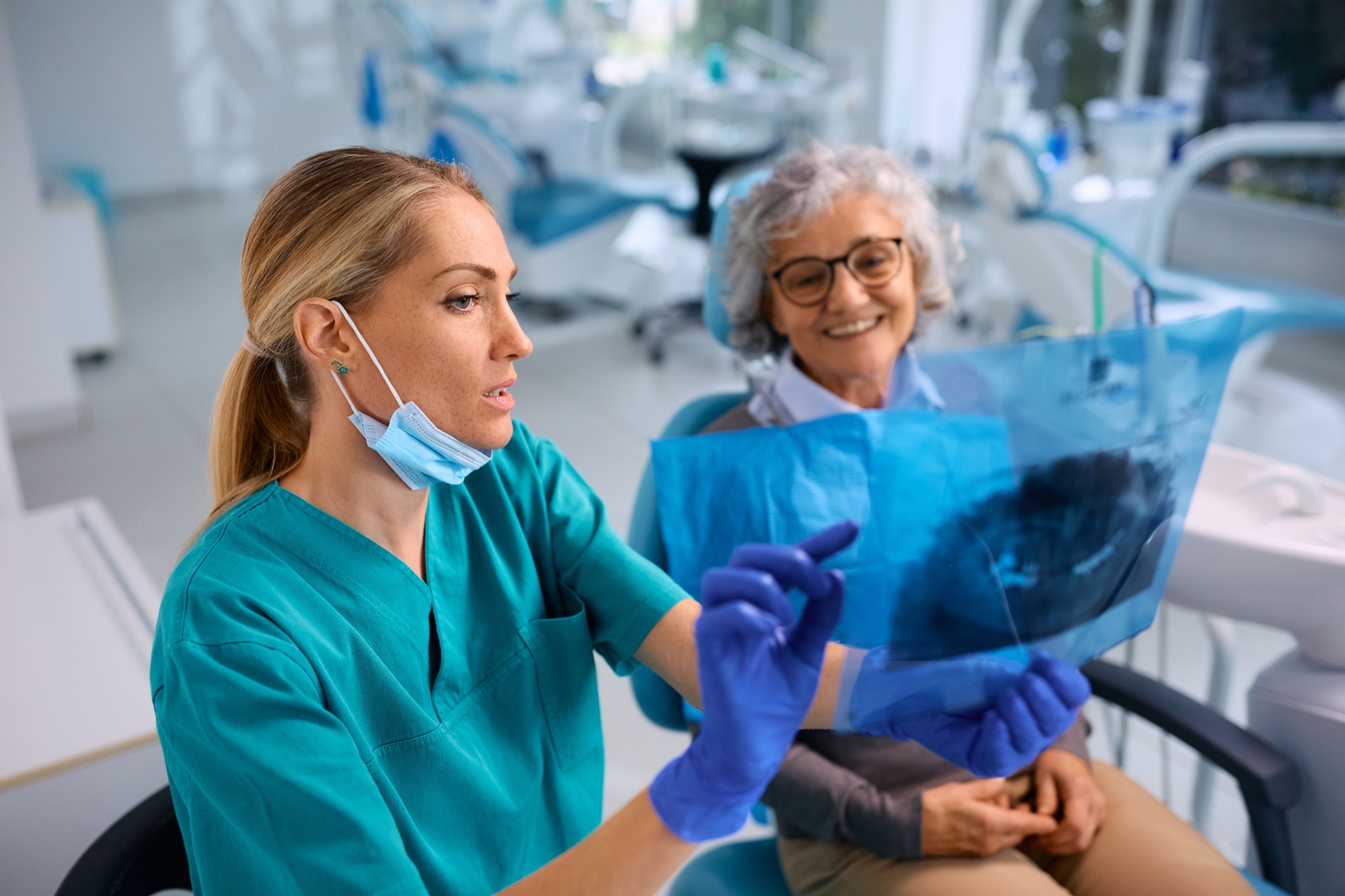 Female dentist showing to senior woman her orthopantomogram during dental appointment.